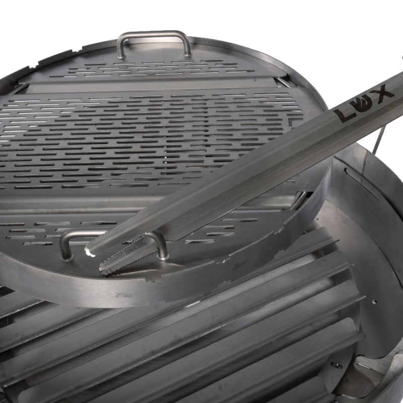 Lux tongs shown using notch in tongs to rotate Versa Grate 360 degrees for precision open fire grilling.