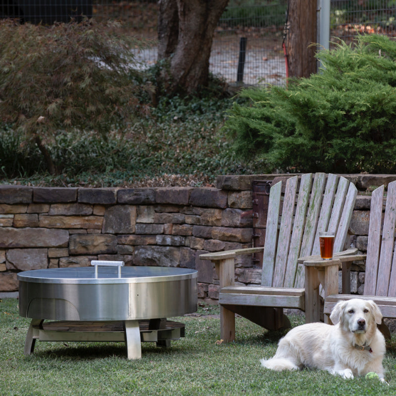 LUX Pro Precision grill in Storage Mode with lid in backyard. Golden Retriever dog laying on ground in front of grill and Adirondack chairs.